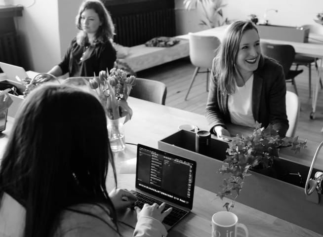 women sitting at long desk doing work